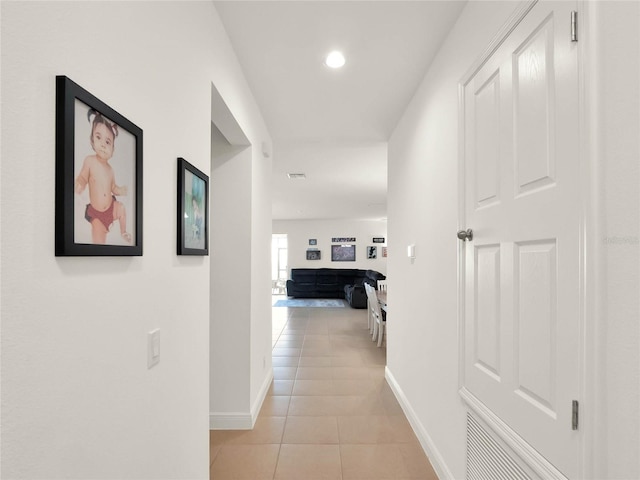 hall featuring recessed lighting, baseboards, and light tile patterned flooring