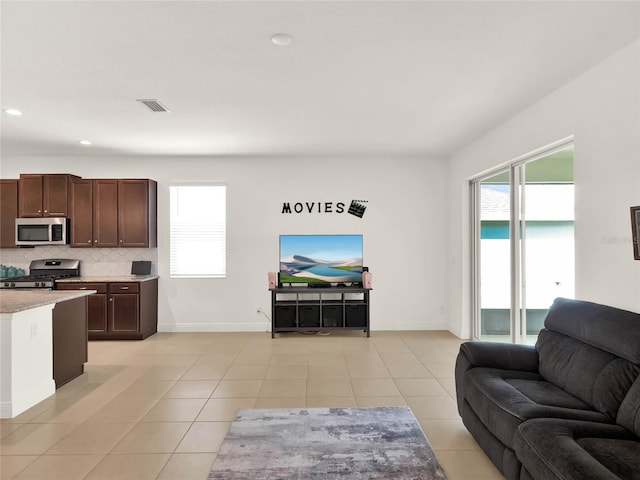 living area featuring recessed lighting, light tile patterned floors, a healthy amount of sunlight, and visible vents