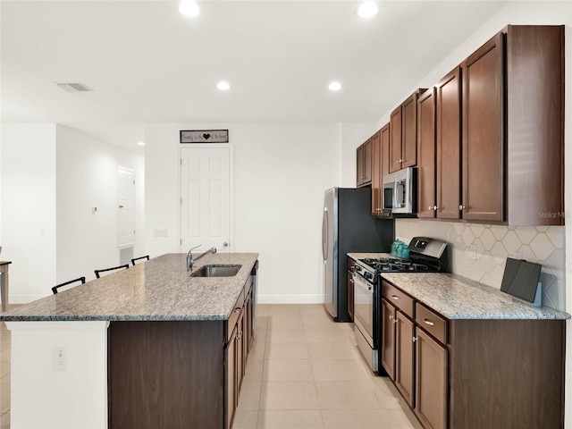 kitchen featuring tasteful backsplash, visible vents, a center island with sink, appliances with stainless steel finishes, and a sink