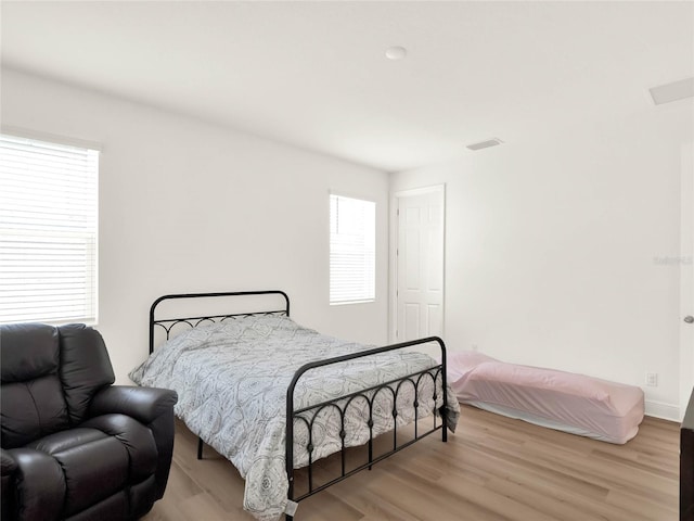 bedroom featuring light wood-style floors, visible vents, and baseboards