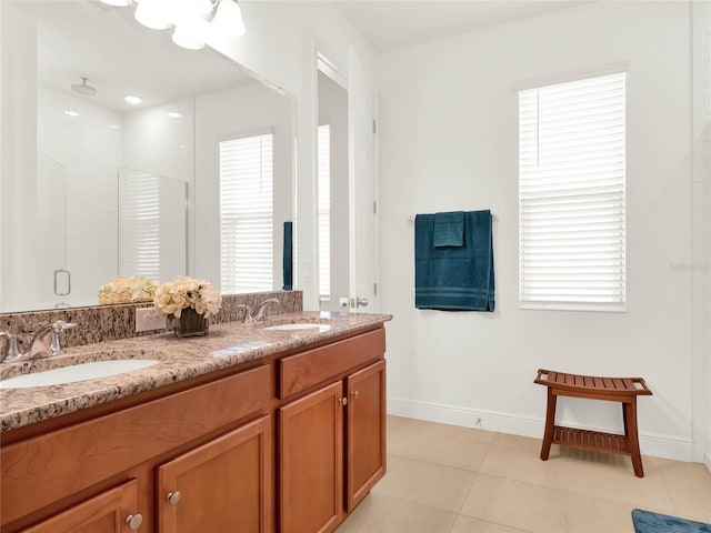 bathroom featuring double vanity, a stall shower, baseboards, and a sink