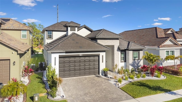 view of front of property featuring a tiled roof, decorative driveway, and a garage