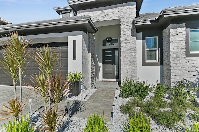 doorway to property with a garage and stucco siding