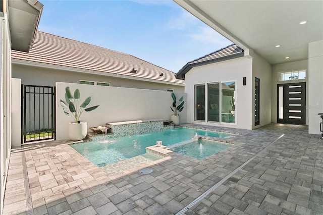 view of swimming pool featuring a pool with connected hot tub, a patio, and fence