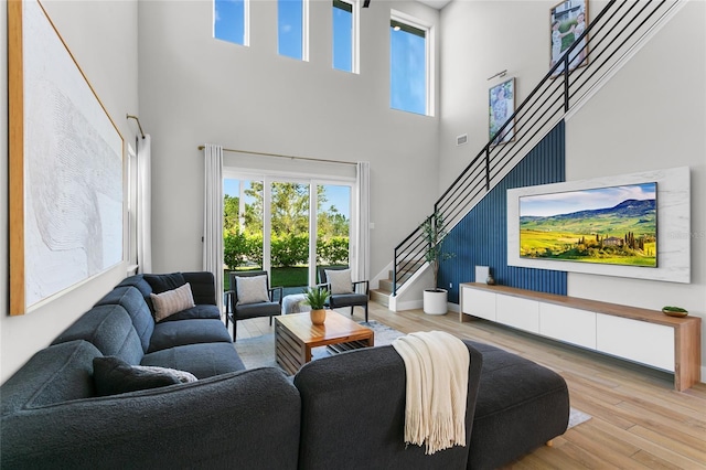 living room featuring stairway, a healthy amount of sunlight, baseboards, and wood finished floors