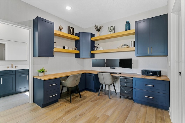 office featuring a sink, recessed lighting, built in desk, and light wood-type flooring