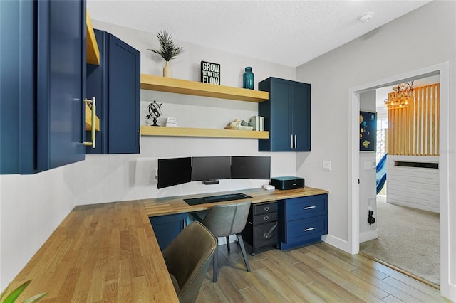 office space with a textured ceiling, built in desk, and light wood finished floors