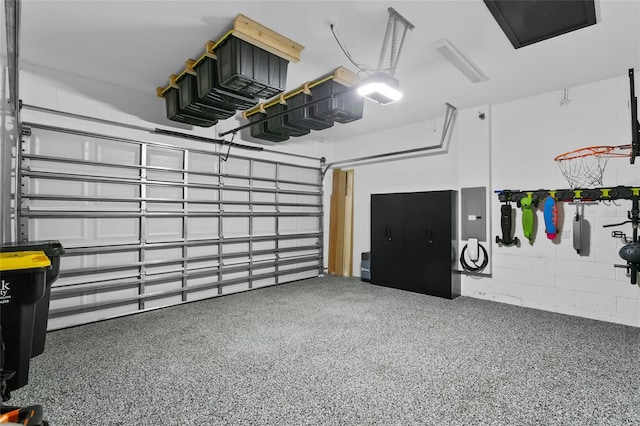 garage featuring electric panel, concrete block wall, and a garage door opener