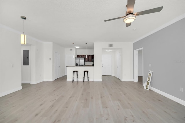 unfurnished living room with electric panel, light wood-style flooring, baseboards, and ceiling fan