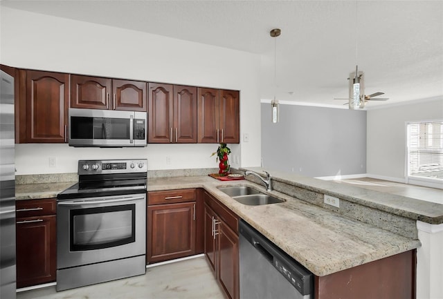 kitchen featuring decorative light fixtures, appliances with stainless steel finishes, a peninsula, a ceiling fan, and a sink