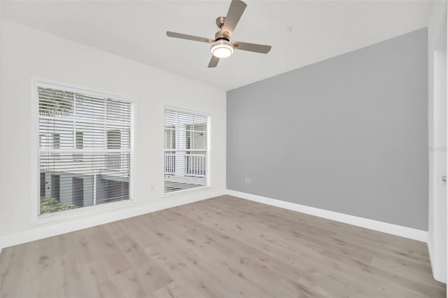 spare room with light wood-style flooring, a ceiling fan, and baseboards