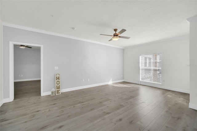 spare room with baseboards, ceiling fan, ornamental molding, wood finished floors, and a textured ceiling