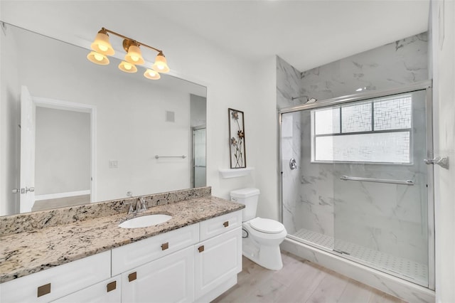 full bath with a marble finish shower, toilet, wood finished floors, and vanity