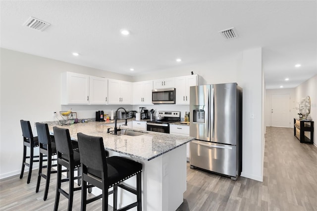 kitchen with visible vents, a breakfast bar, a peninsula, a sink, and appliances with stainless steel finishes