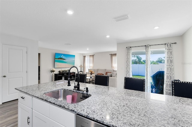 kitchen with white cabinetry, plenty of natural light, open floor plan, and a sink