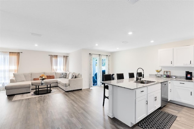 kitchen with wood finished floors, a breakfast bar, a sink, dishwasher, and open floor plan