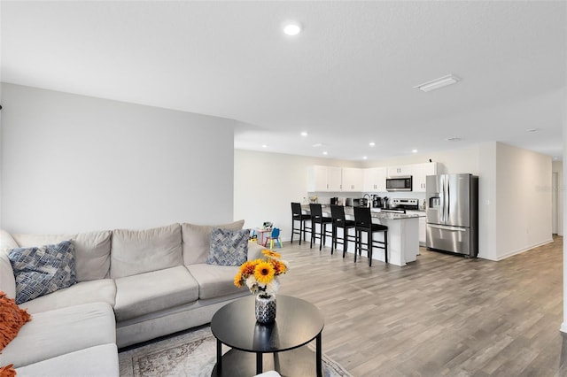 living room with recessed lighting, light wood-type flooring, and baseboards