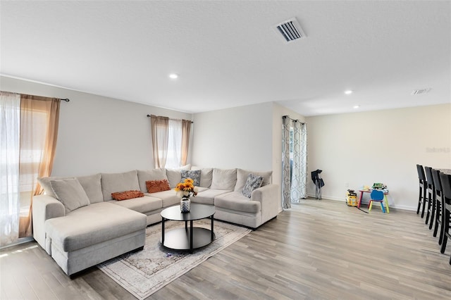 living room with light wood-style flooring, recessed lighting, and visible vents