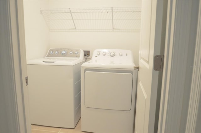 clothes washing area featuring light tile patterned floors, laundry area, and washing machine and clothes dryer