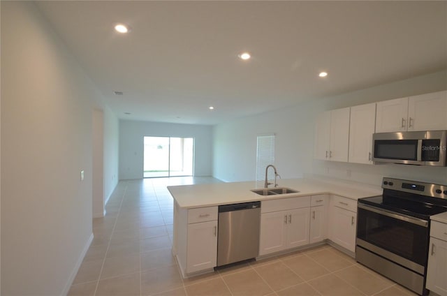 kitchen featuring a sink, open floor plan, white cabinetry, stainless steel appliances, and a peninsula