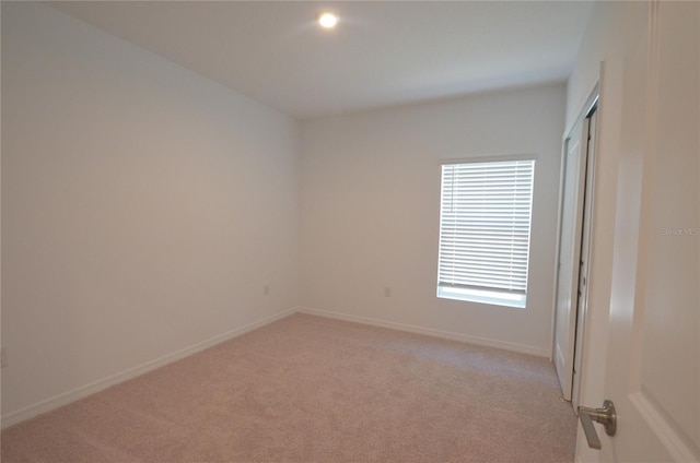 spare room with baseboards and light carpet