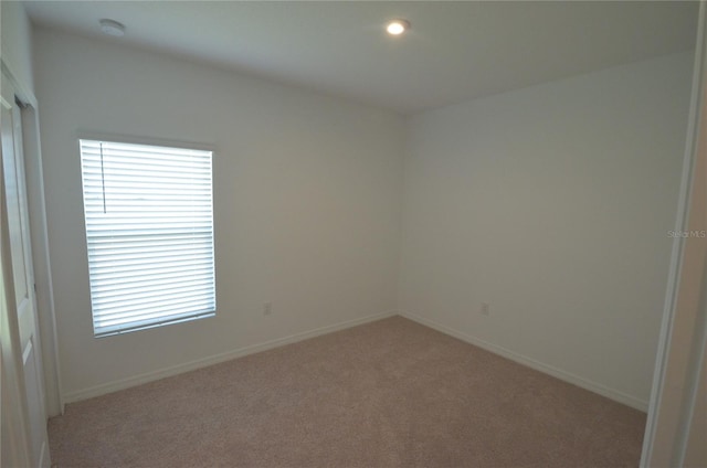 unfurnished room featuring light colored carpet and baseboards