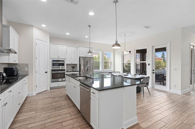 kitchen featuring a sink, plenty of natural light, backsplash, appliances with stainless steel finishes, and wood tiled floor