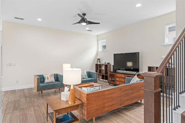 living room with ceiling fan, visible vents, light wood-style flooring, and stairs