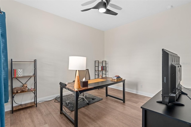 home office with baseboards, ceiling fan, and light wood finished floors