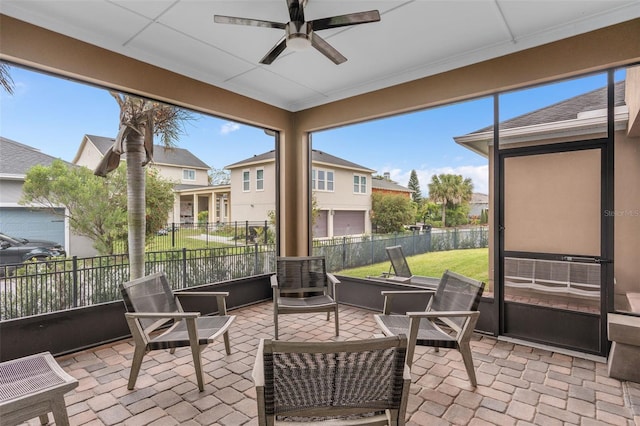 sunroom featuring a ceiling fan and a residential view