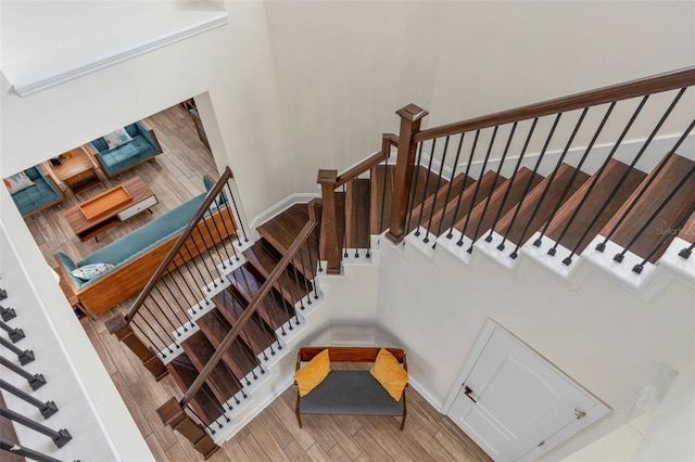 staircase with baseboards, a high ceiling, and wood finished floors