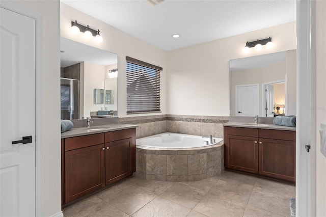 full bathroom with a bath, a shower stall, two vanities, and a sink