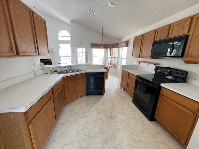 kitchen with visible vents, brown cabinets, a peninsula, black appliances, and a sink