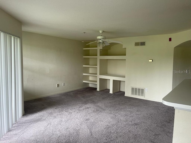 unfurnished living room with carpet, arched walkways, visible vents, and ceiling fan