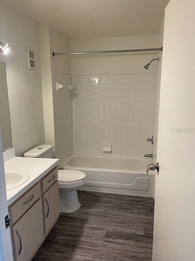 bathroom with shower / bathtub combination, toilet, wood finished floors, and vanity