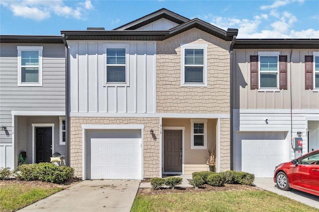 townhome / multi-family property with concrete driveway, an attached garage, and board and batten siding