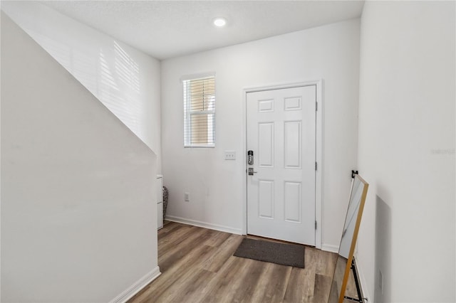 foyer entrance with baseboards and wood finished floors