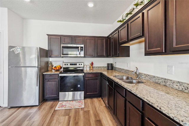 kitchen featuring a sink, dark brown cabinetry, light wood-style flooring, and stainless steel appliances