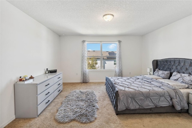 bedroom featuring baseboards, light carpet, and a textured ceiling