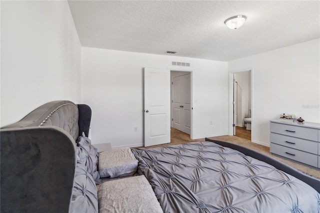 bedroom with visible vents, baseboards, a textured ceiling, and carpet flooring