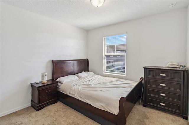 bedroom featuring light colored carpet, a textured ceiling, and baseboards