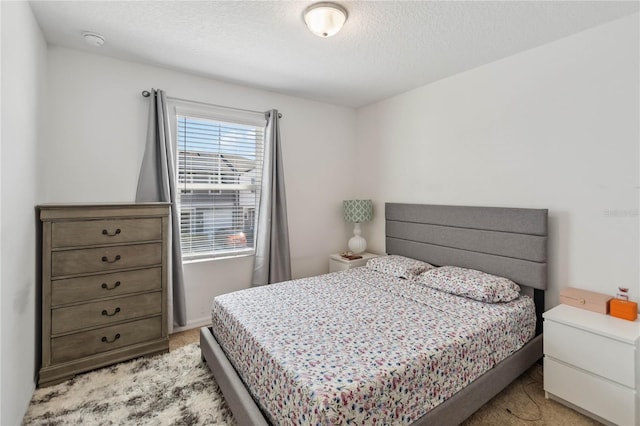 bedroom with light colored carpet and a textured ceiling