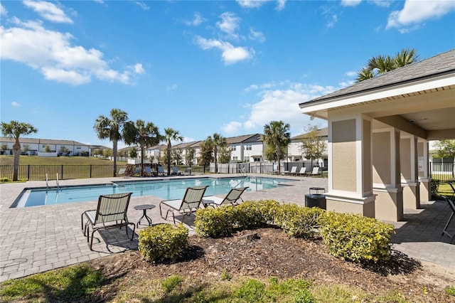 pool with a patio area, a residential view, and fence