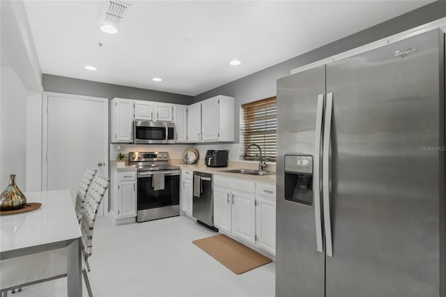 kitchen featuring a sink, appliances with stainless steel finishes, white cabinets, and light countertops