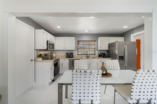 kitchen featuring a sink, decorative backsplash, light countertops, white cabinets, and appliances with stainless steel finishes