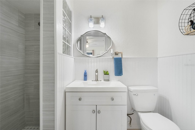 bathroom featuring a wainscoted wall, a shower stall, vanity, and toilet