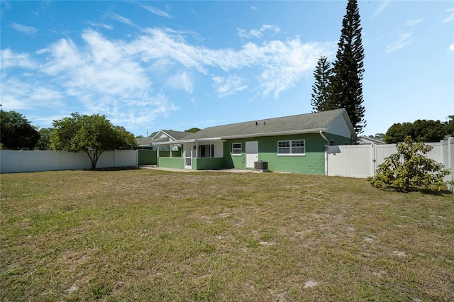 rear view of property featuring a yard, central AC, a fenced backyard, and a gate