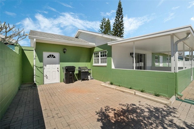 exterior space featuring concrete block siding, a patio area, and fence