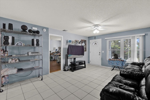 tiled living room featuring a textured ceiling, visible vents, and ceiling fan