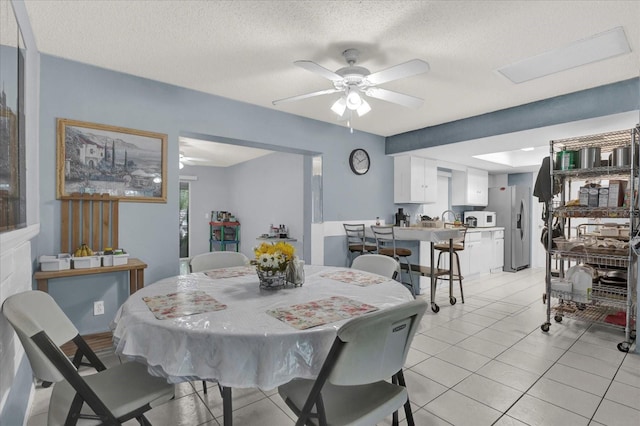 dining area featuring light tile patterned flooring, a ceiling fan, and a textured ceiling